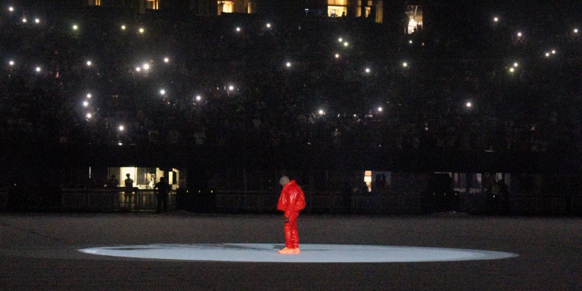 Kanye West, seul en doudoune et pantalon rouges au milieu du Mercedes-Benz Stadium à Atlanta pour la première listening party de Donda.